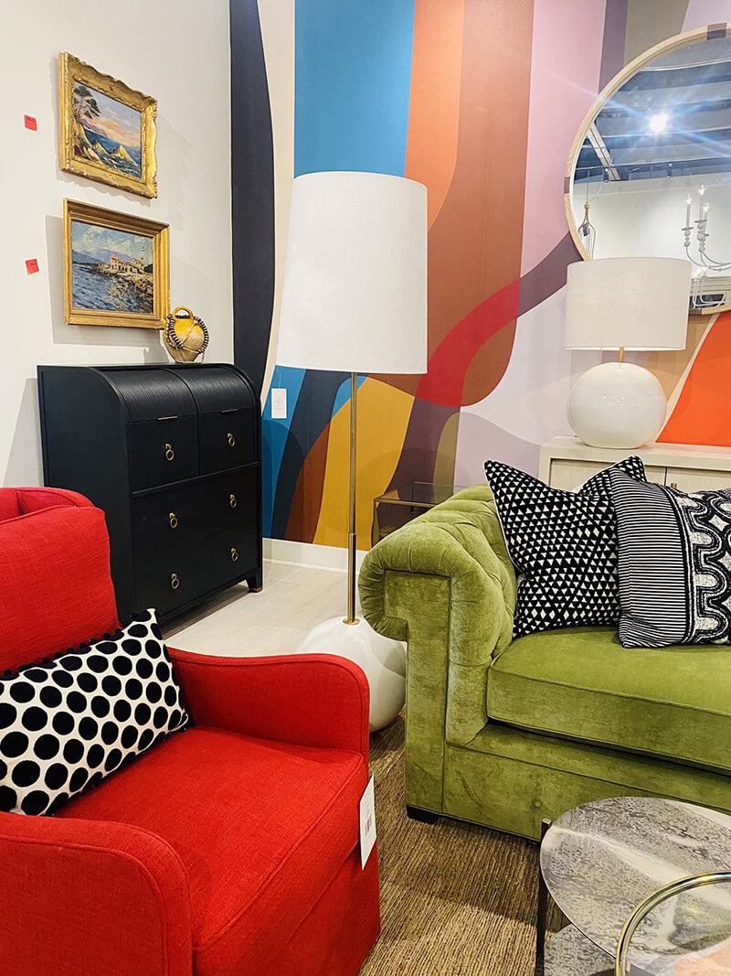 Vibrant bold colors such as a red upholstered chair and leaf green upholstered sofa with black and white patterned pillows